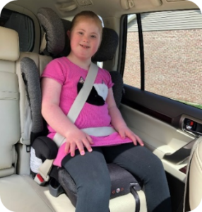 image Child with Down Syndrome riding in a booster seat in a passenger vehicle